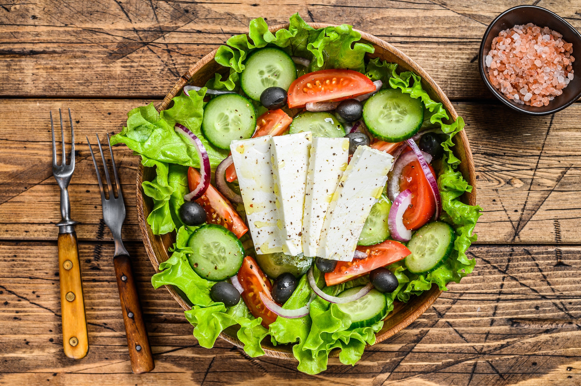 Greek salad with fresh vegetables and feta cheese. Wooden background. Top view